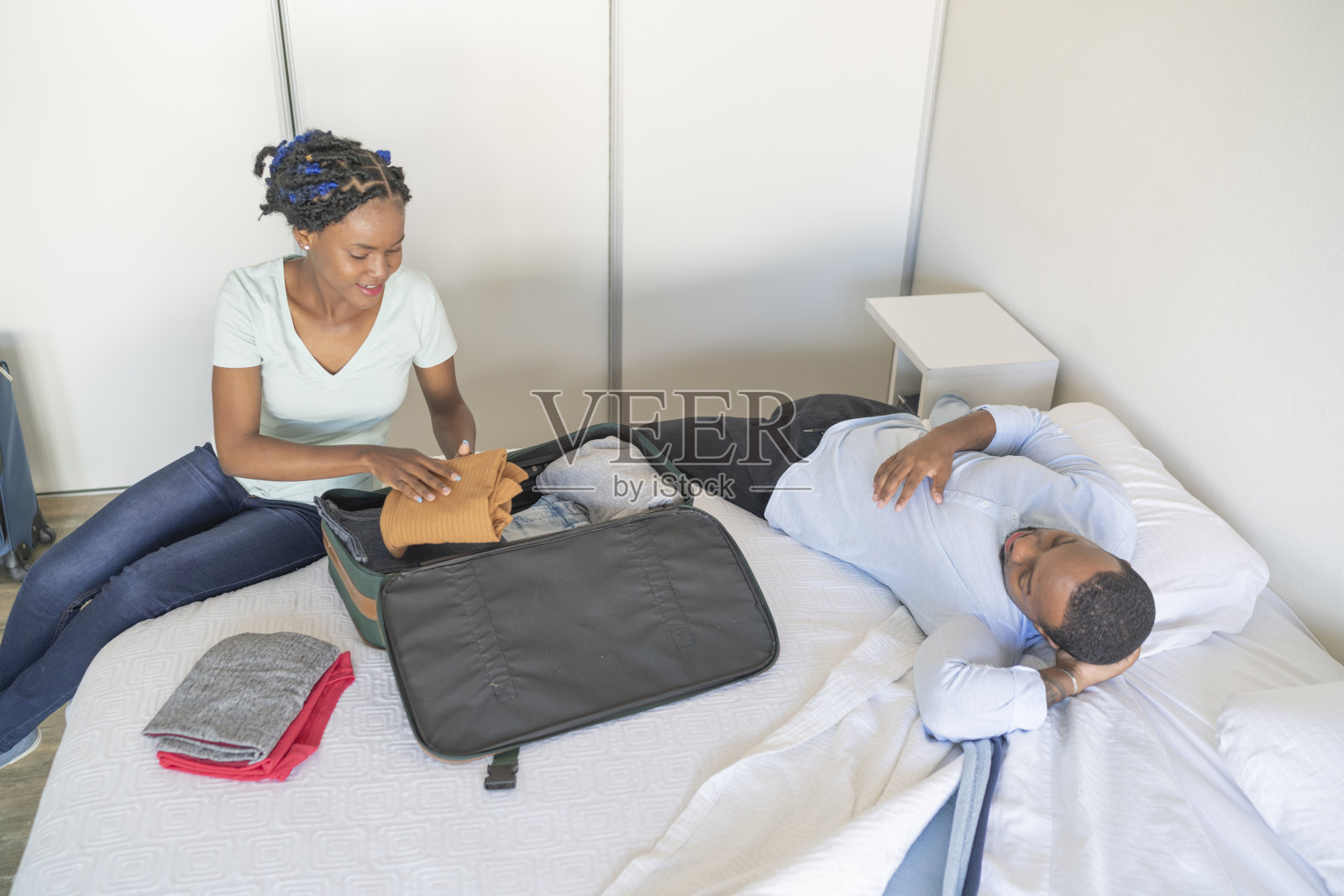 在丈夫休息时,非裔美国人妻子在整理衣服照片摄影图片