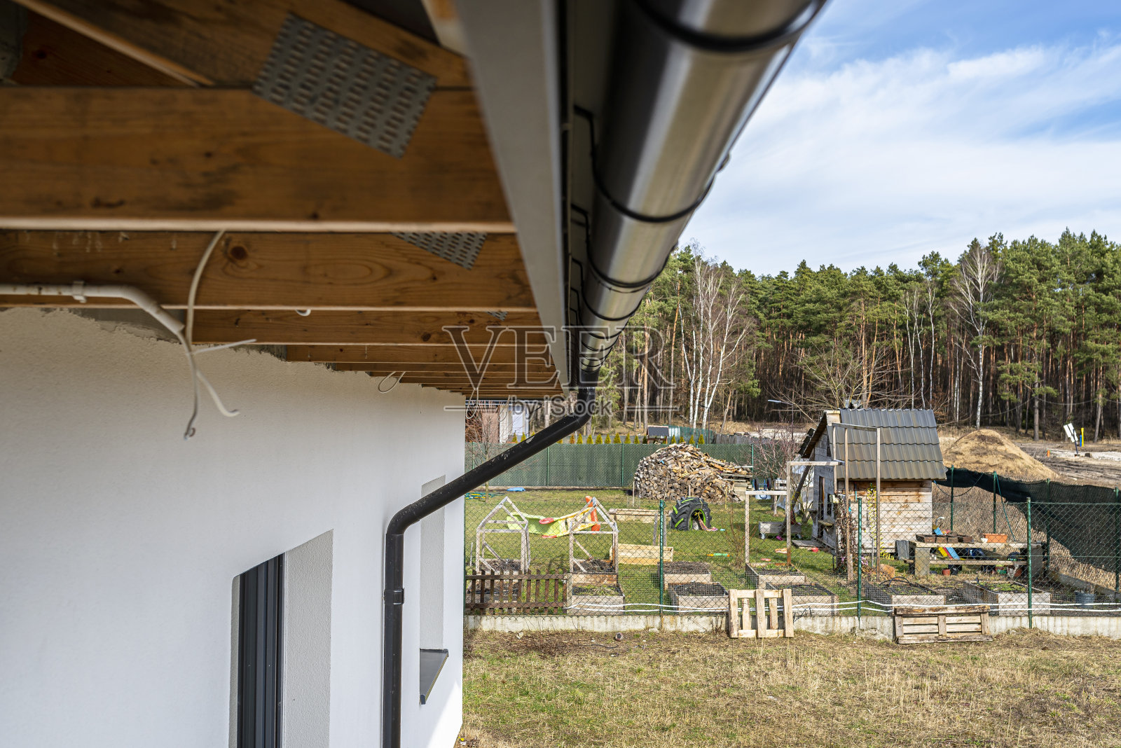 一个金属黑色的水槽,屋顶上覆盖着瓷砖,背景是森林,底部视图。照片摄影图片