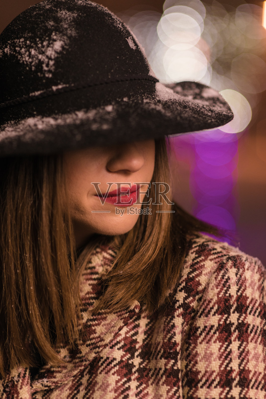 小女孩站在圣诞树前的彩灯上。一个女孩在圣诞节独自在公园里照片摄影图片