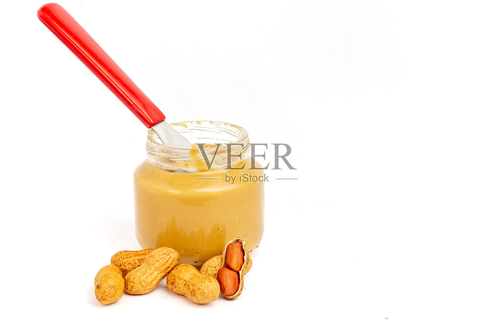 玻璃罐花生酱,黄油刀和花生在前面的白色背景。照片摄影图片