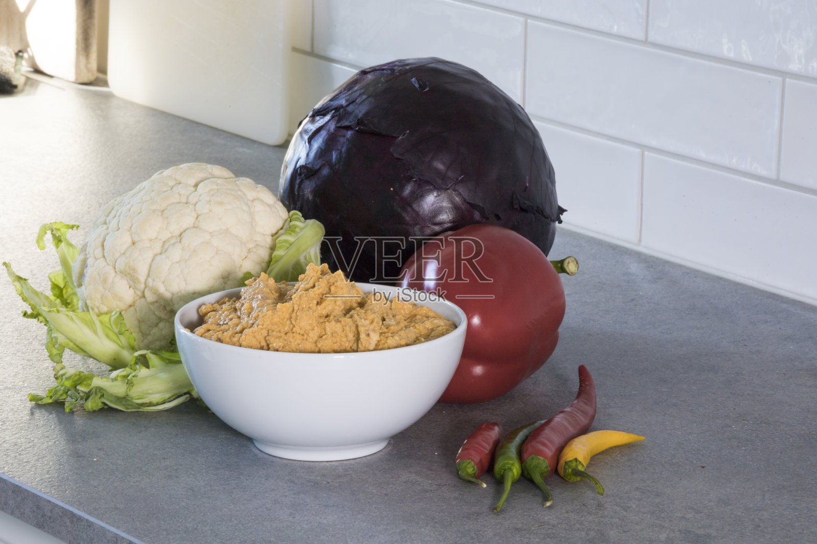 一碗自制的鹰嘴豆泥,周围是蔬菜。照片摄影图片