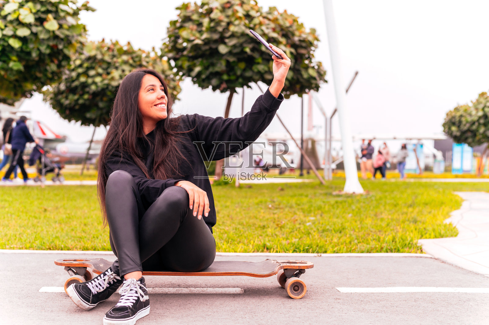 美丽的滑冰女孩在公园里自拍。照片摄影图片