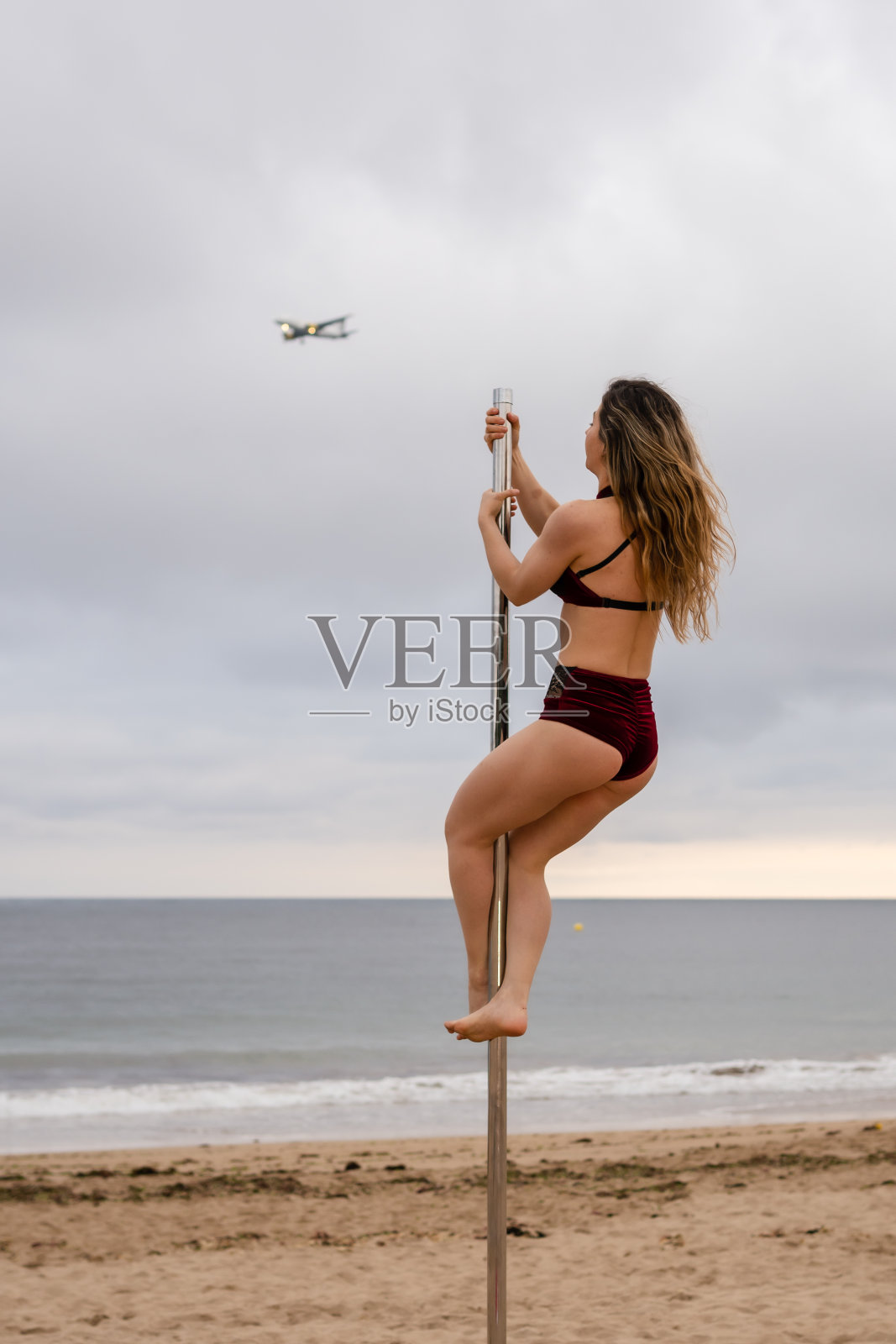 年轻的白人女孩表演钢管舞在美丽的海滩。杂技演员在法国亨达亚海滩的沙滩上表演钢管舞。欣赏IC内的美景照片摄影图片