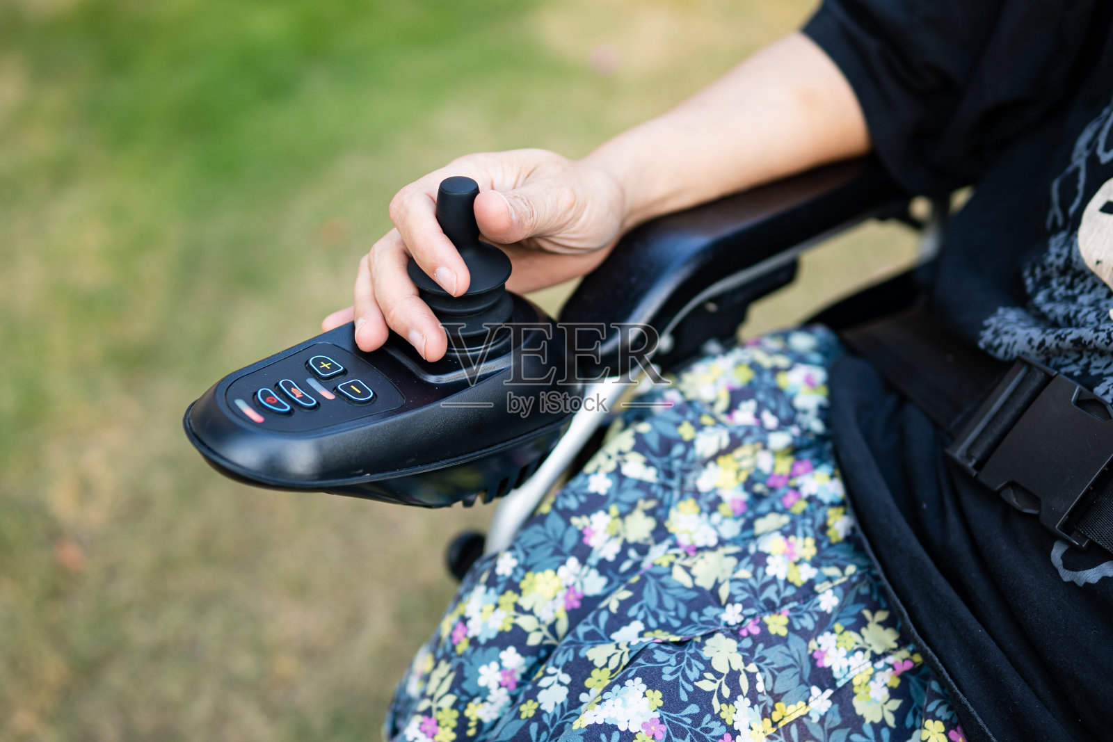 亚洲女士女病人坐在电动轮椅上,用操纵杆和遥控器在护理院病房里,健康有力的医疗理念照片摄影图片