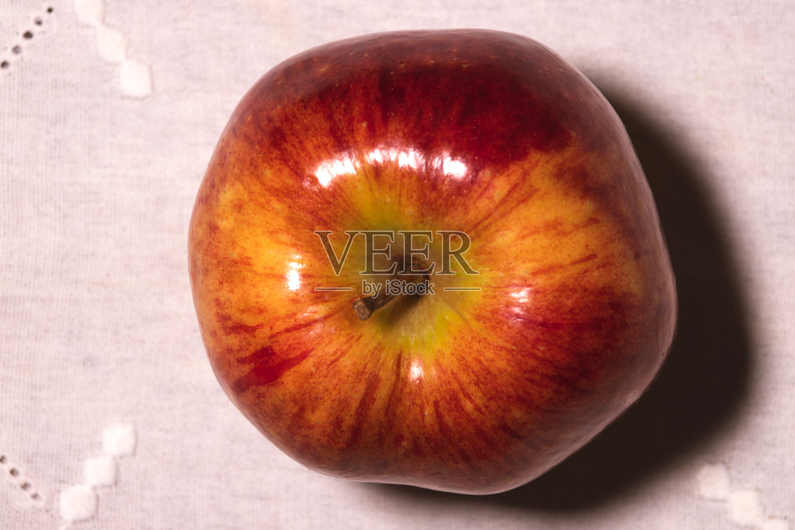 俯视图,一个诱人的熟苹果铺在白色绣花桌布上。照片摄影图片