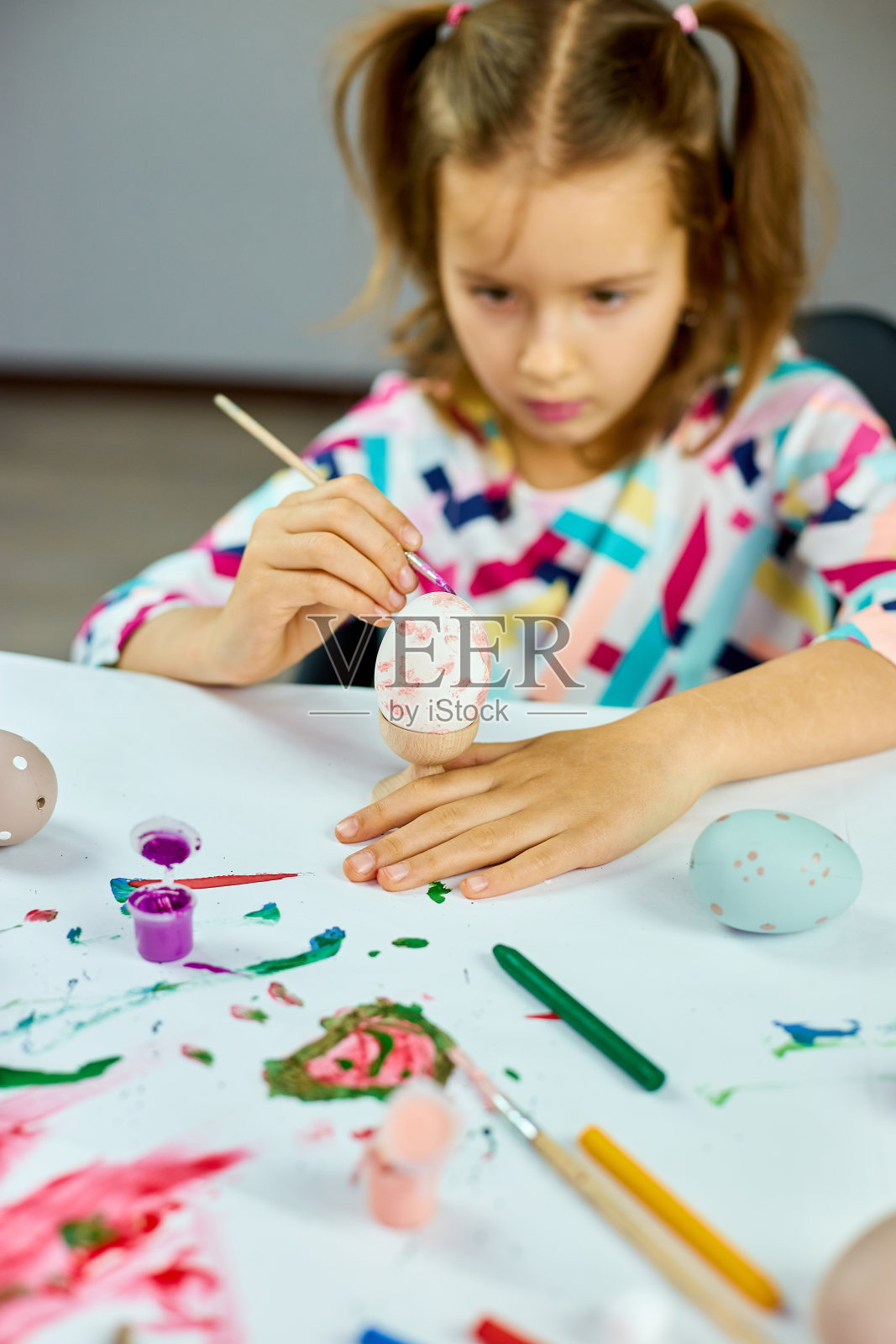 快乐的小女孩画画,在家里用刷子画鸡蛋。照片摄影图片