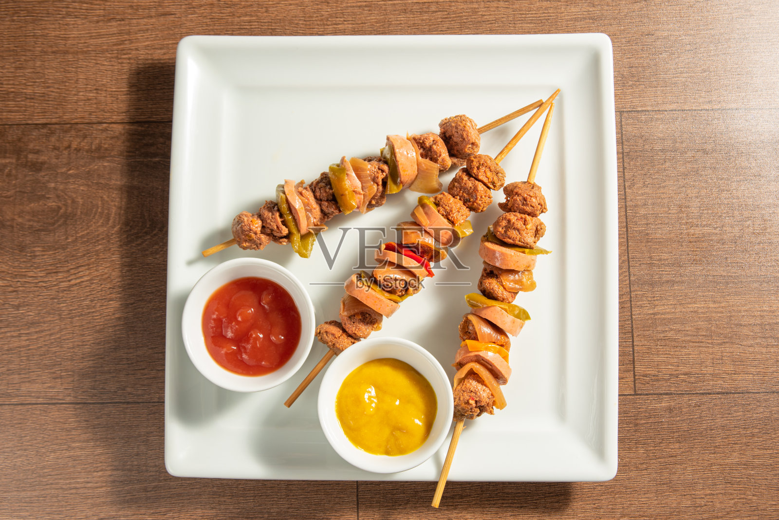 纯素食品,纯素串和酱汁在一个白色的盘子上,在木头上,俯视图。照片摄影图片