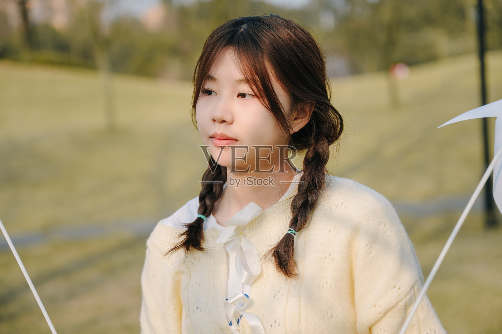 一个美丽的亚洲女孩和一个纸风车在一个阳光明媚的日子在草地上照片摄影图片