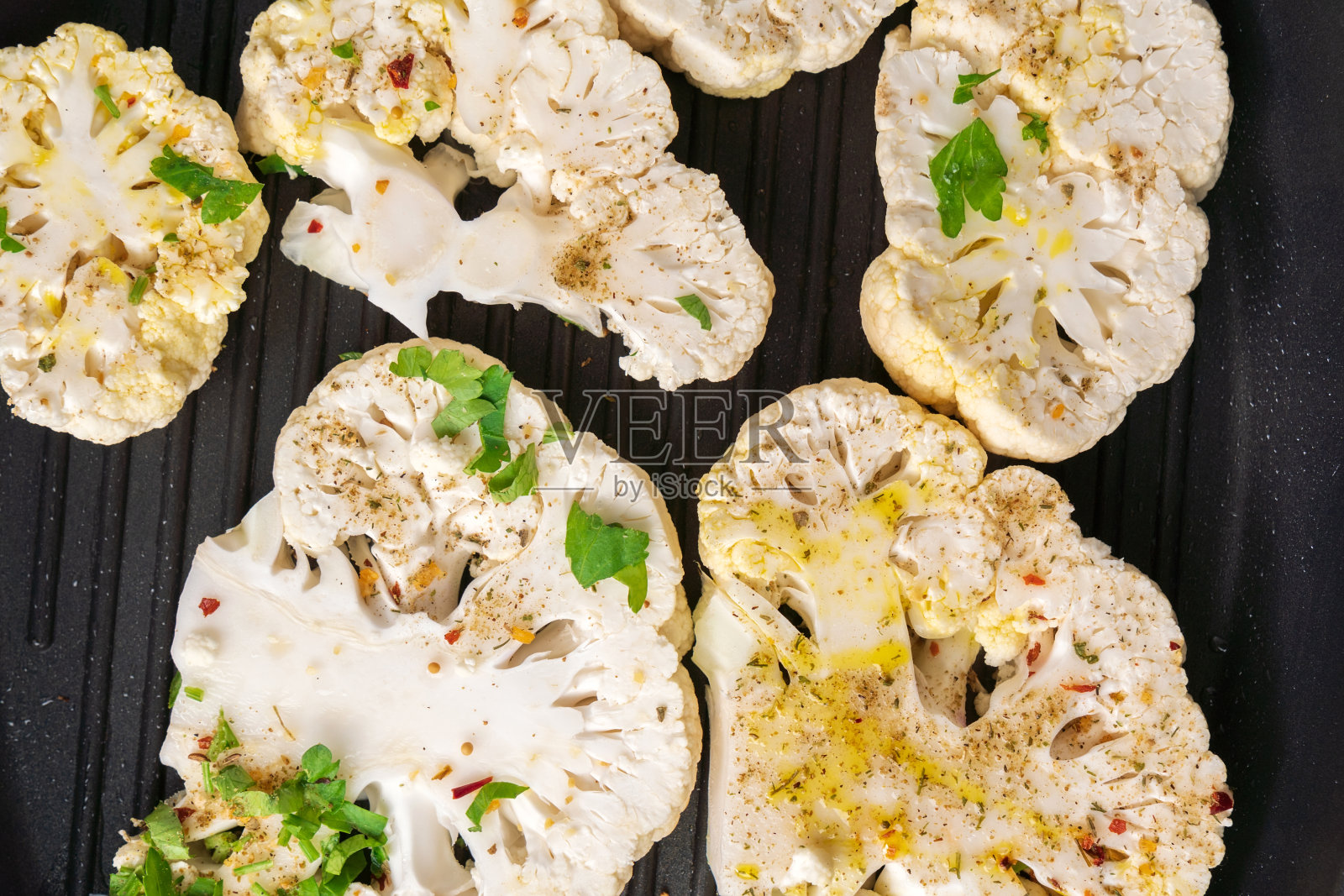 花椰菜牛排与香料在锅中煮。蔬菜肉类替代品。照片摄影图片