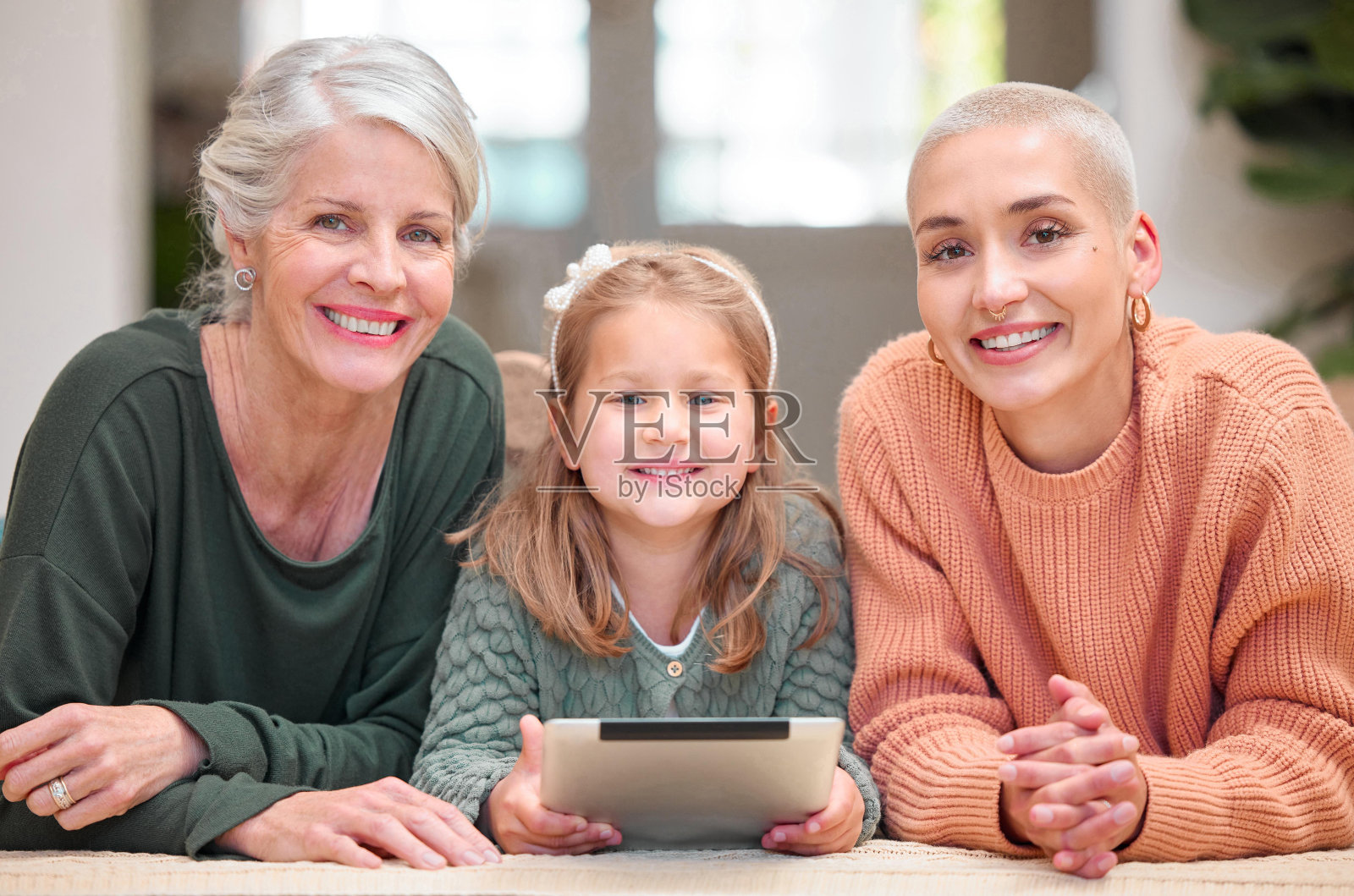 一个成熟的女人与她的女儿和孙女一起使用数码平板电脑的肖像照片摄影图片