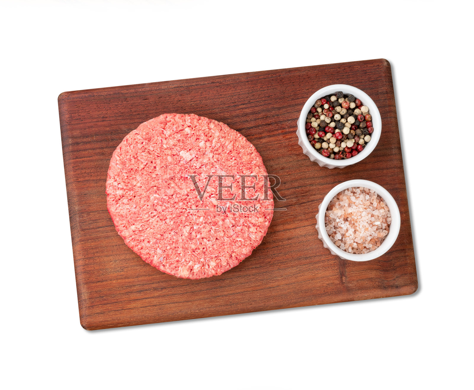 生肉汉堡铺在木板上,白色背景上点缀着调味料照片摄影图片