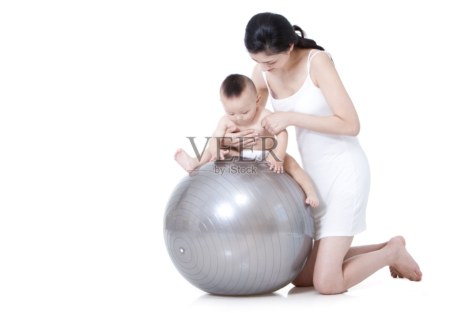 母亲指导婴儿在健身球上玩照片摄影图片