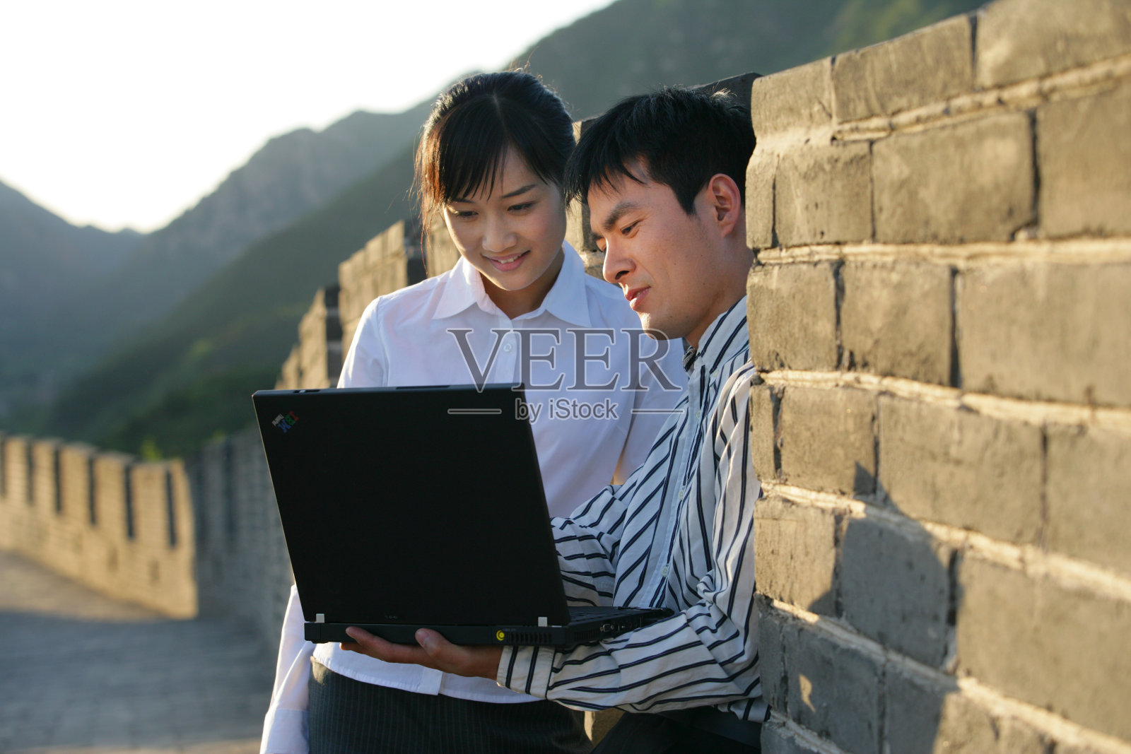 两位商务人士在长城上使用笔记本电脑照片摄影图片