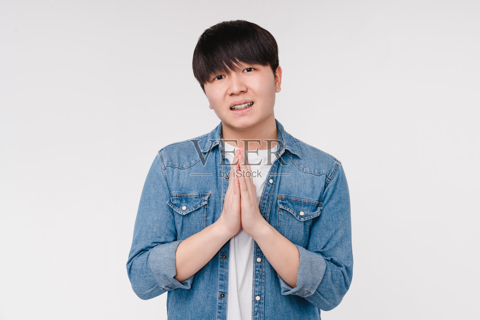 年轻的亚洲韩国男子学生男孩乞求冥想祈祷孤立在白色背景。禅宗般的心情,让人安详照片摄影图片