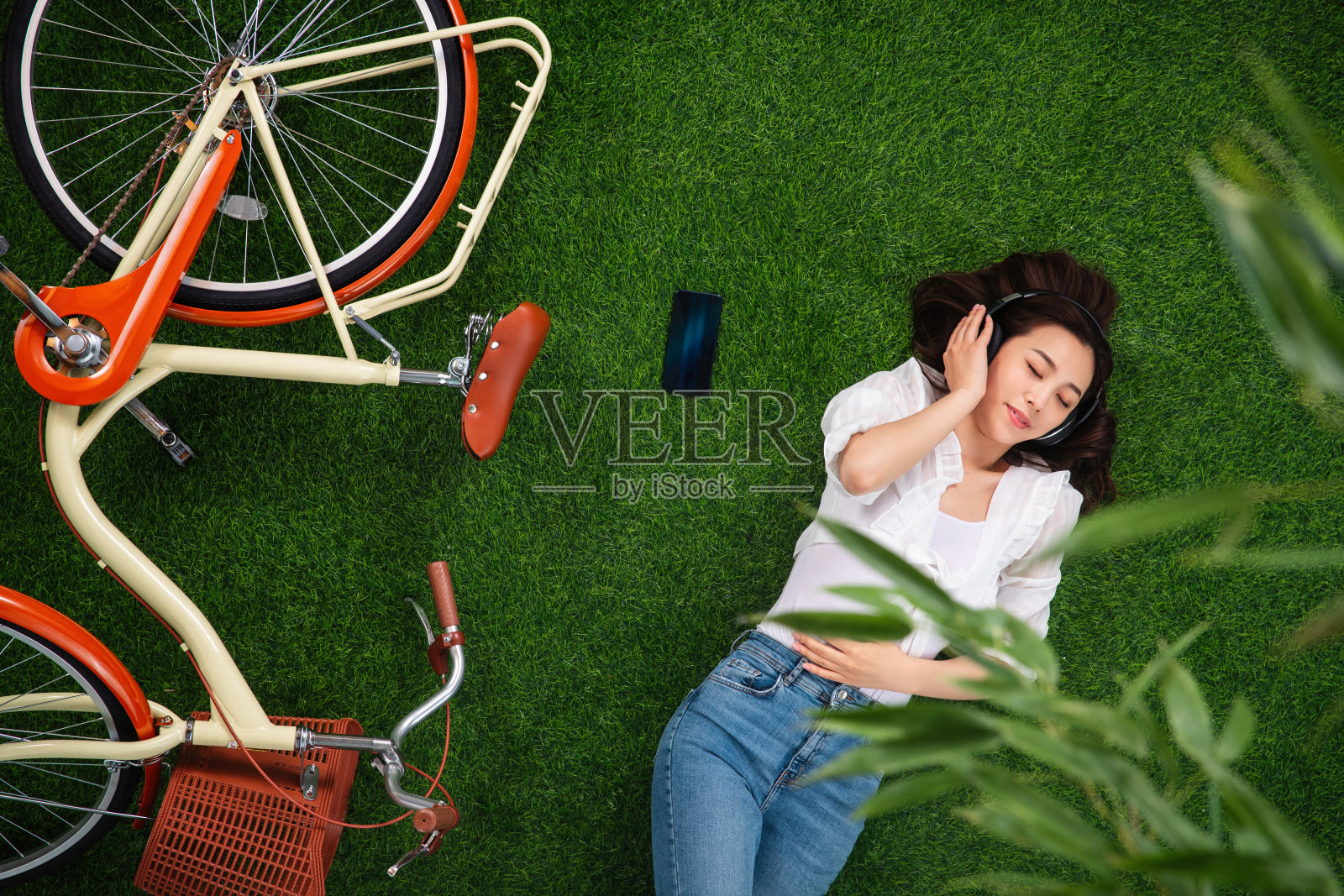 躺在草地上听音乐的年轻女人照片摄影图片