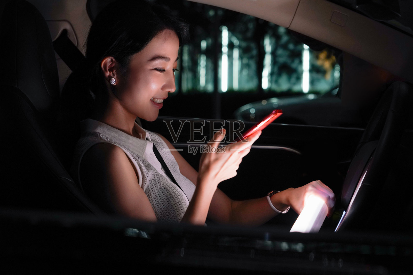 夜晚青年女人坐在汽车里使用手机照片摄影图片