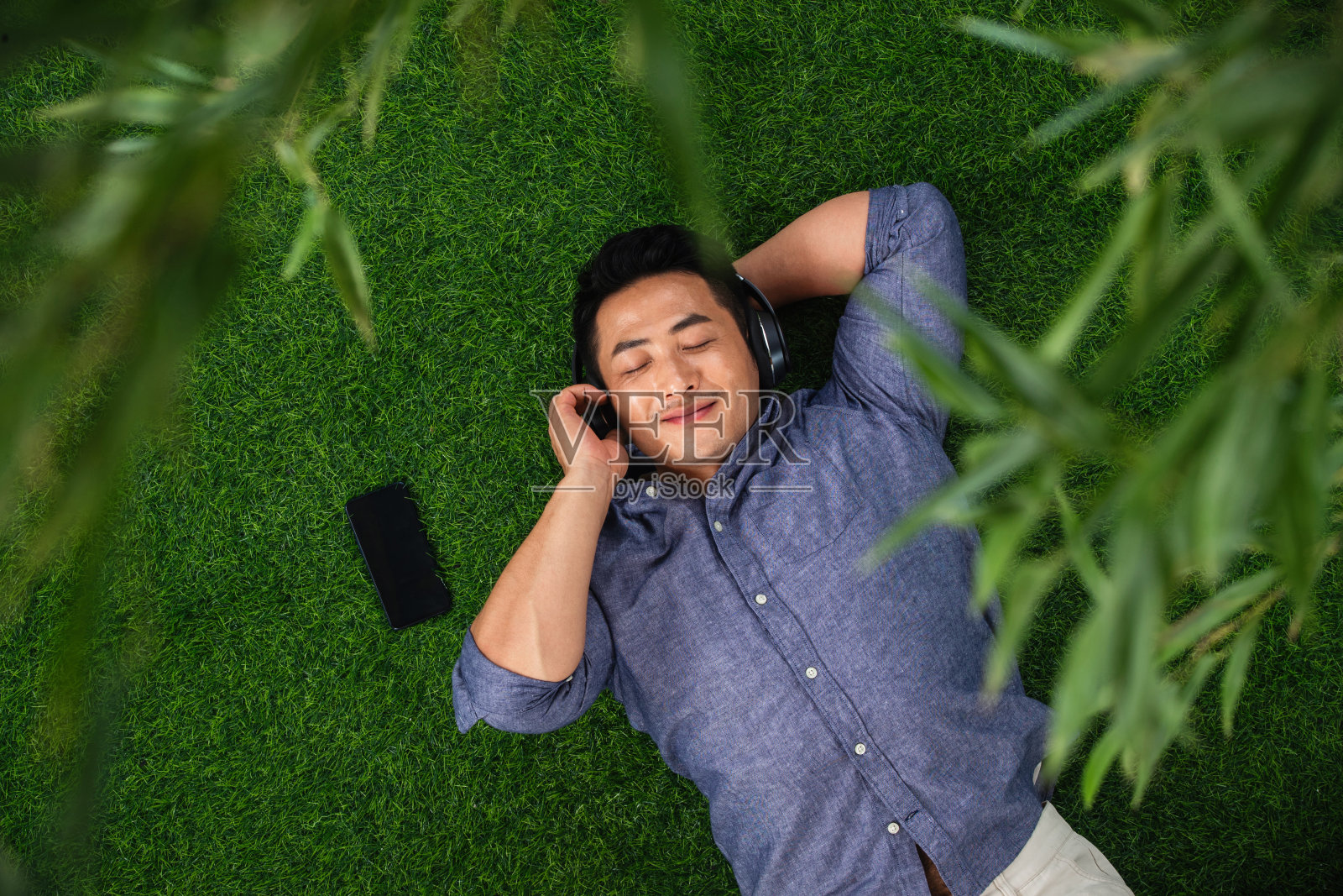 躺在草地上听音乐的青年男人照片摄影图片