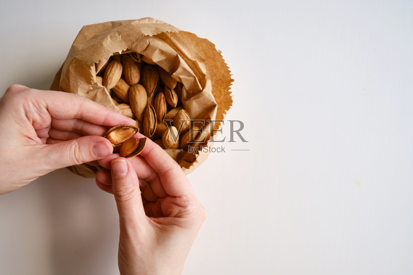 用牛皮纸袋装杏仁,背景色淡。健康食品。健康的素食自然小吃。有机食品。坚果特写照片摄影图片