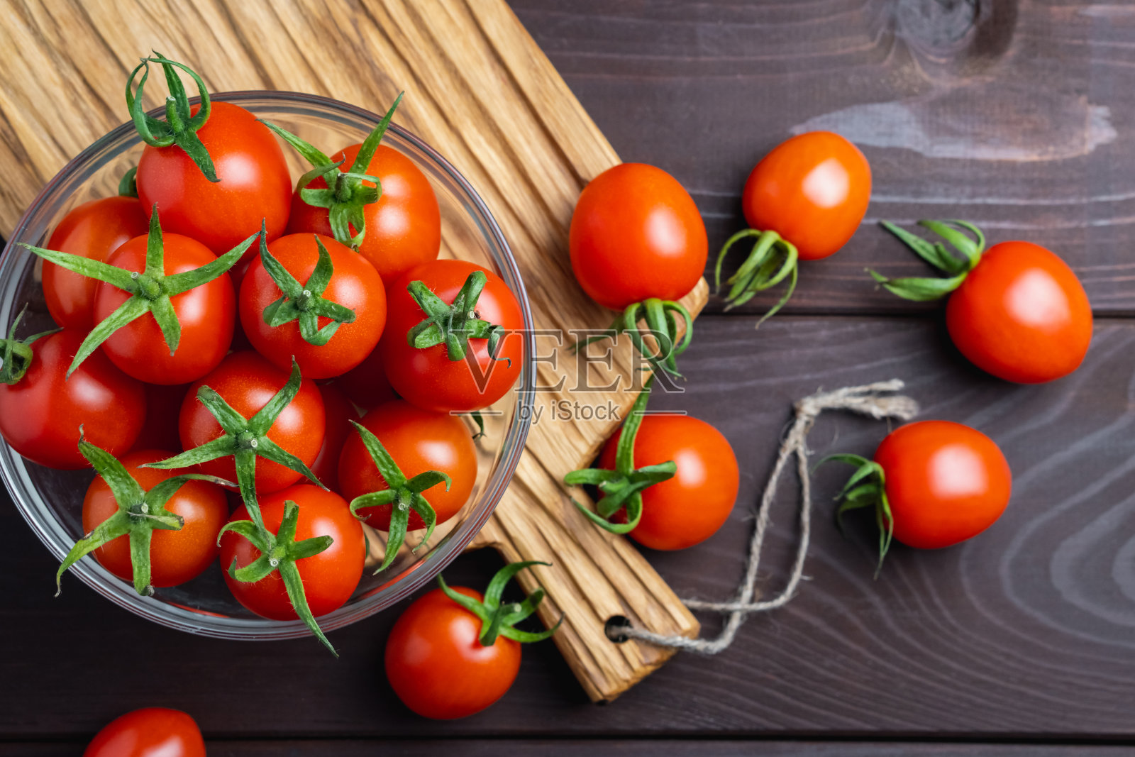 红番茄放在玻璃碗里,放在木桌上的切菜板上。有机健康食品。烹饪原料照片摄影图片