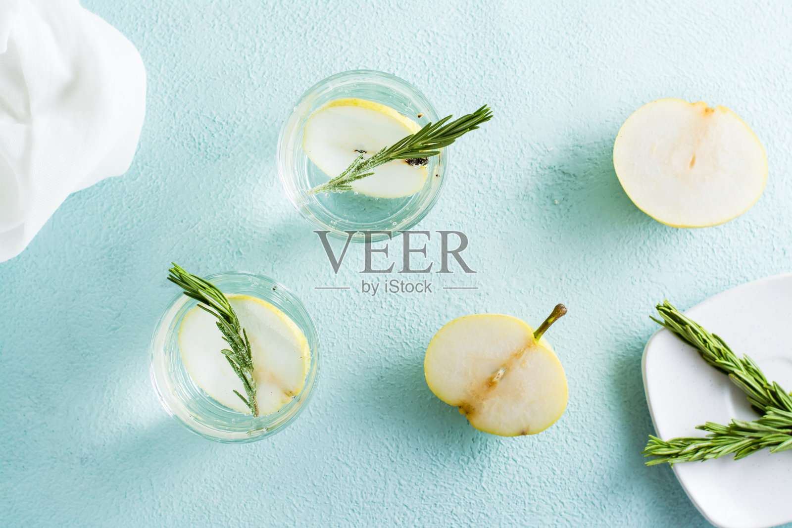 桌上有一杯清凉的矿泉水和盛在玻璃杯里的梨片。自制的饮料。俯视图照片摄影图片