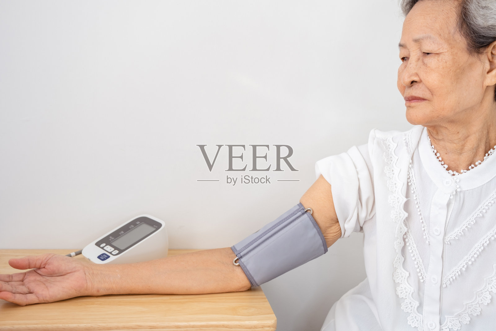 图为,身穿白色衬衫、头发花白的亚洲女性在接种新冠肺炎疫苗之前,正在进行压力测量。照片摄影图片