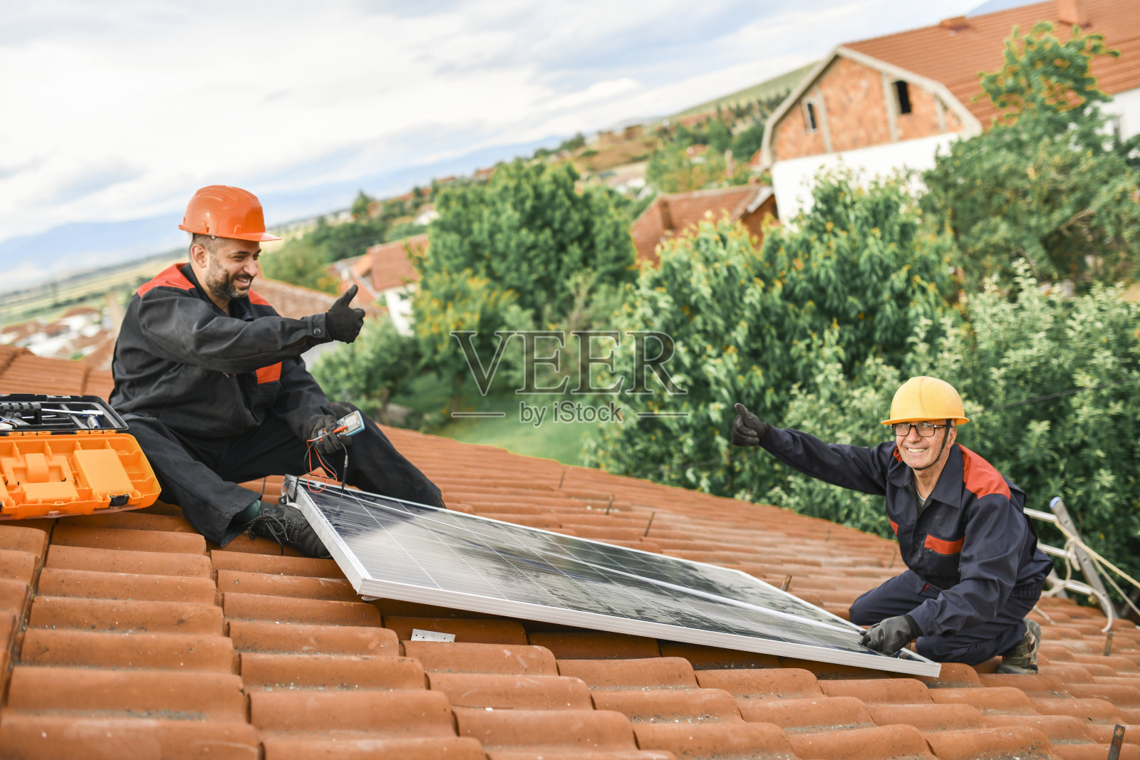 两名不同年代的工人在安装太阳能电池板时互相竖起大拇指照片摄影图片