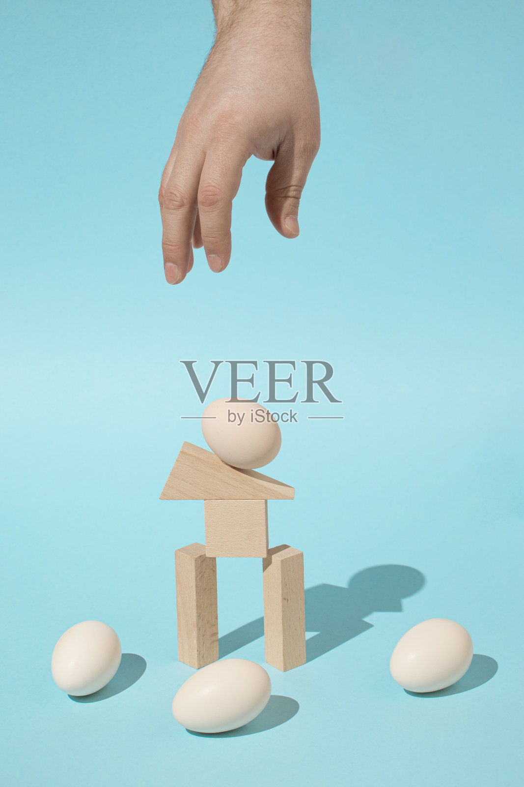 时尚的超现实主义阳光组成与鸡蛋,人的手和木制几何元素在明亮的浅蓝色背景。最小的架构概念。照片摄影图片