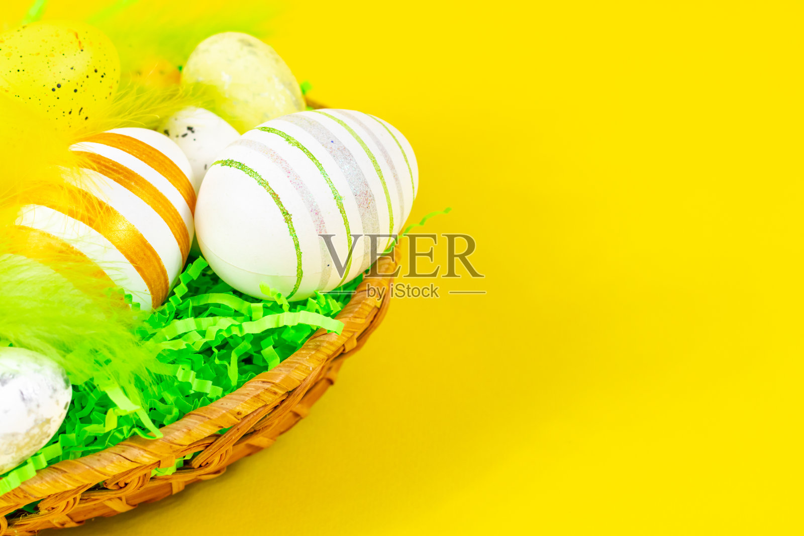 复活节鸟巢与蛋和羽毛在黄色背景的特写。铭文的地方。复活节的概念。照片摄影图片