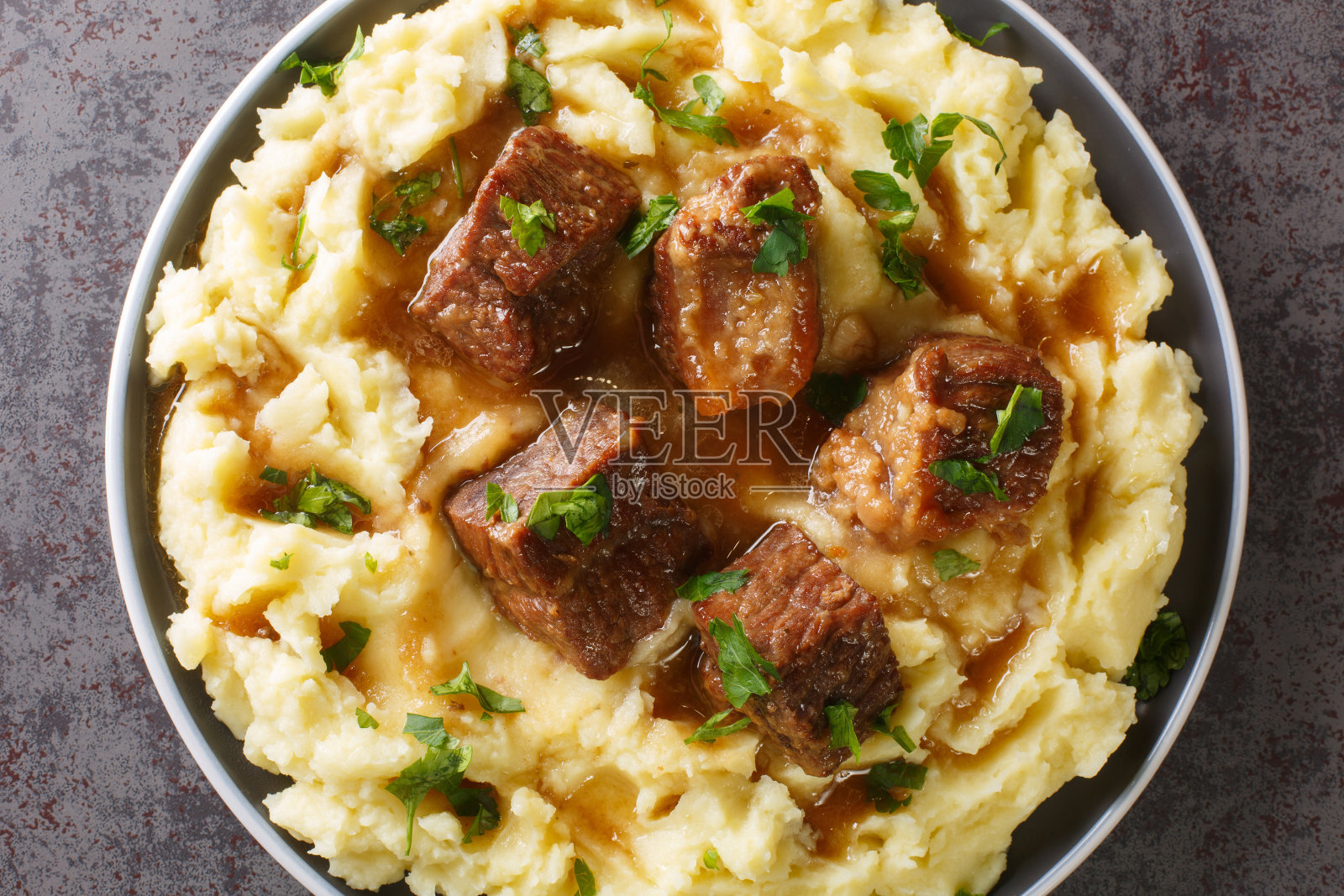 盘子里的希腊慢炖牛肉配上辛辣的肉汁,配上土豆泥。水平的俯视图照片摄影图片