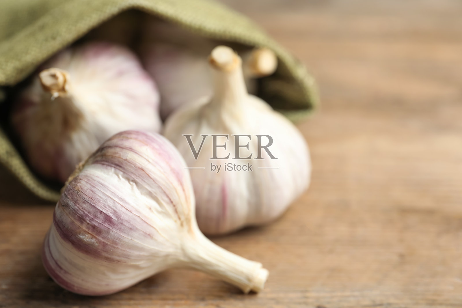 新鲜的未剥皮的大蒜球茎在木制的桌子上,特写与文字的空间。有机产品照片摄影图片