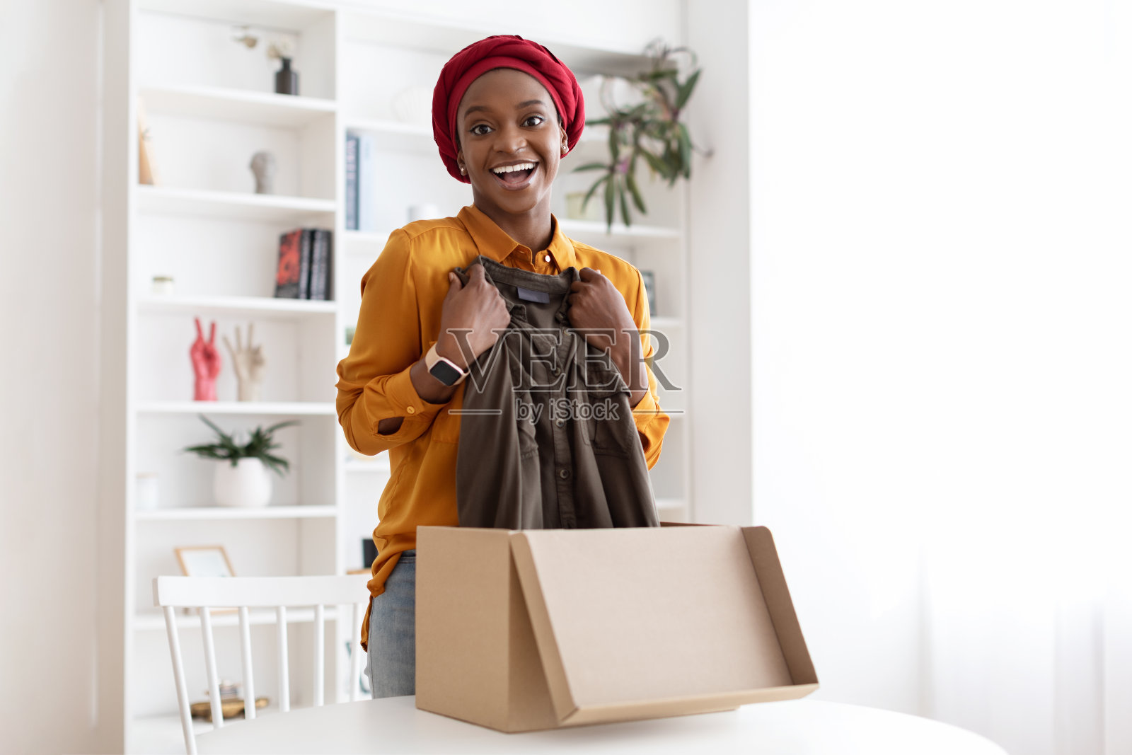 高兴的非洲裔美国妇女从网上商店得到包裹照片摄影图片
