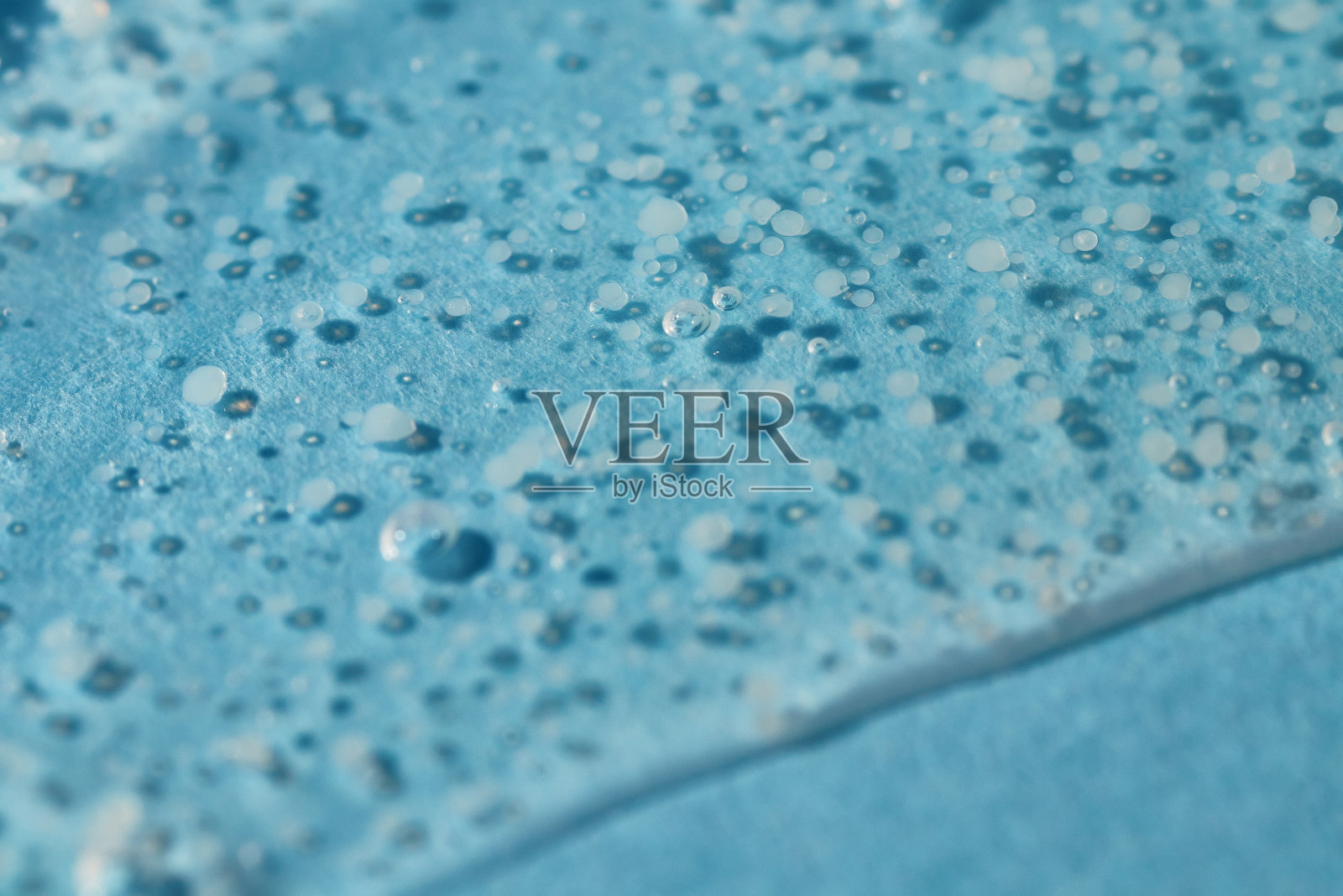 光滑磨砂洗刷凝胶滴在蓝色背景上。照片摄影图片