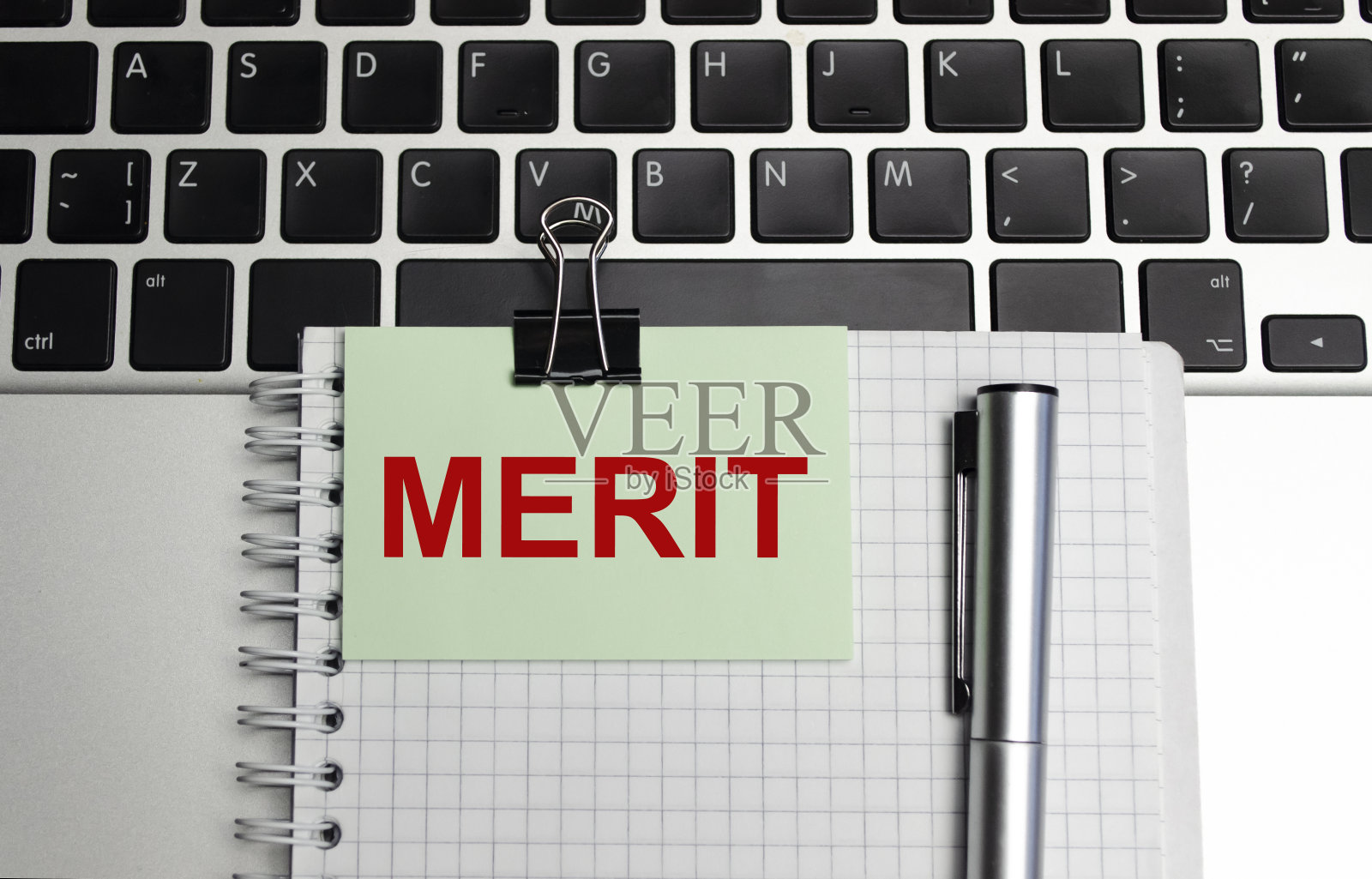 在一个白色背景的放大镜上,一支笔和一张纸与文字功绩业务照片摄影图片