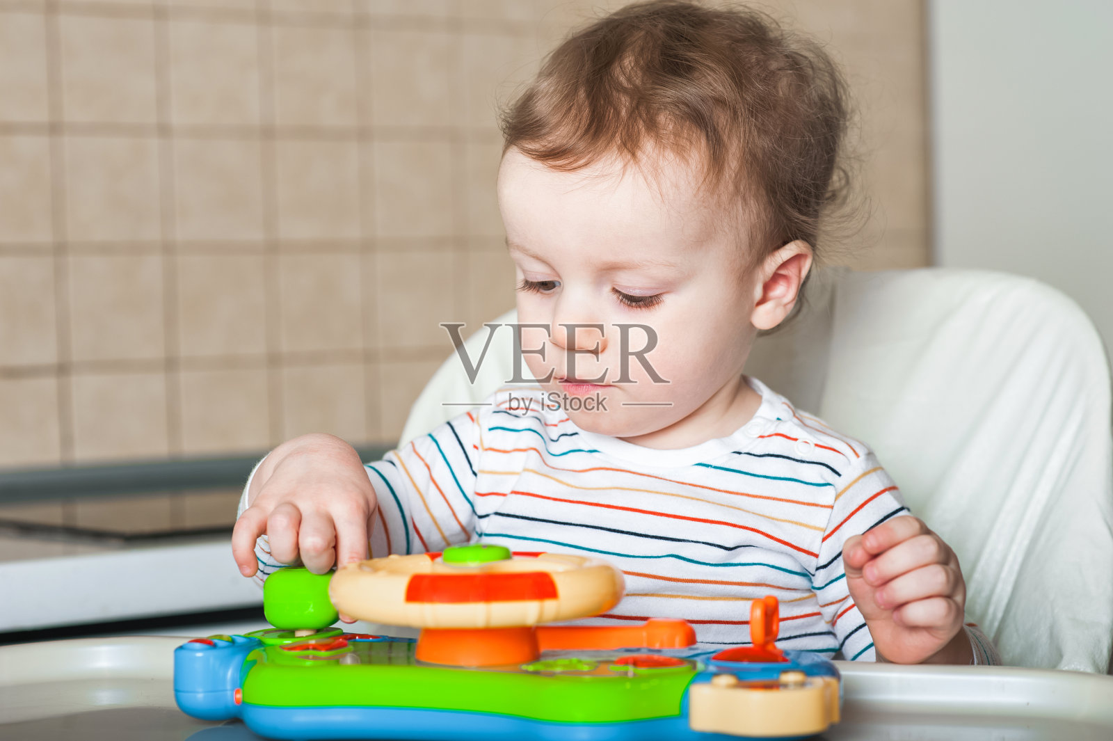 小男孩在喂食桌上玩玩具。照片摄影图片