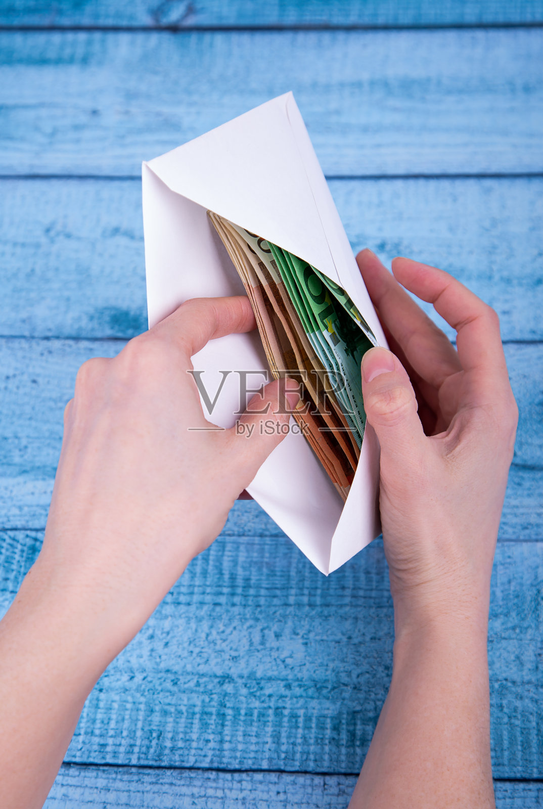 手里拿着一个开着的信封,上面印着蓝色的钱照片摄影图片
