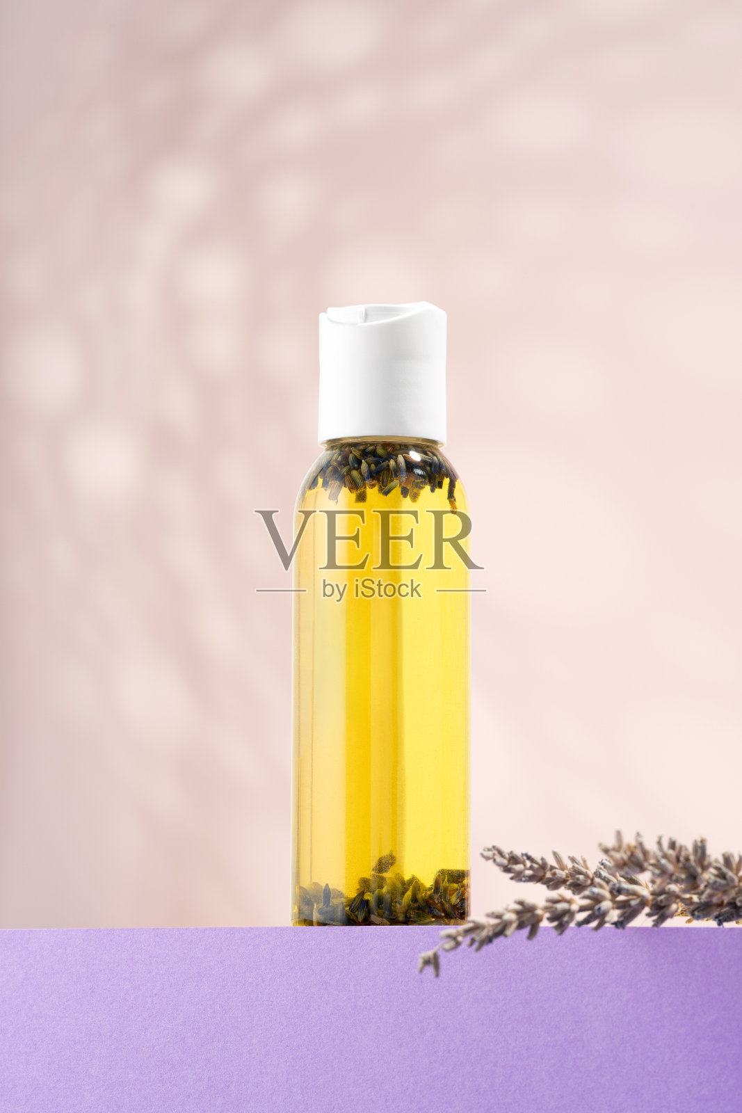 一瓶薰衣草精油,紫色讲台上的薰衣草花。在浅色背景下沐浴用的化妆品精油。植物疗法、香薰疗法、自我护理、干燥皮肤营养照片摄影图片