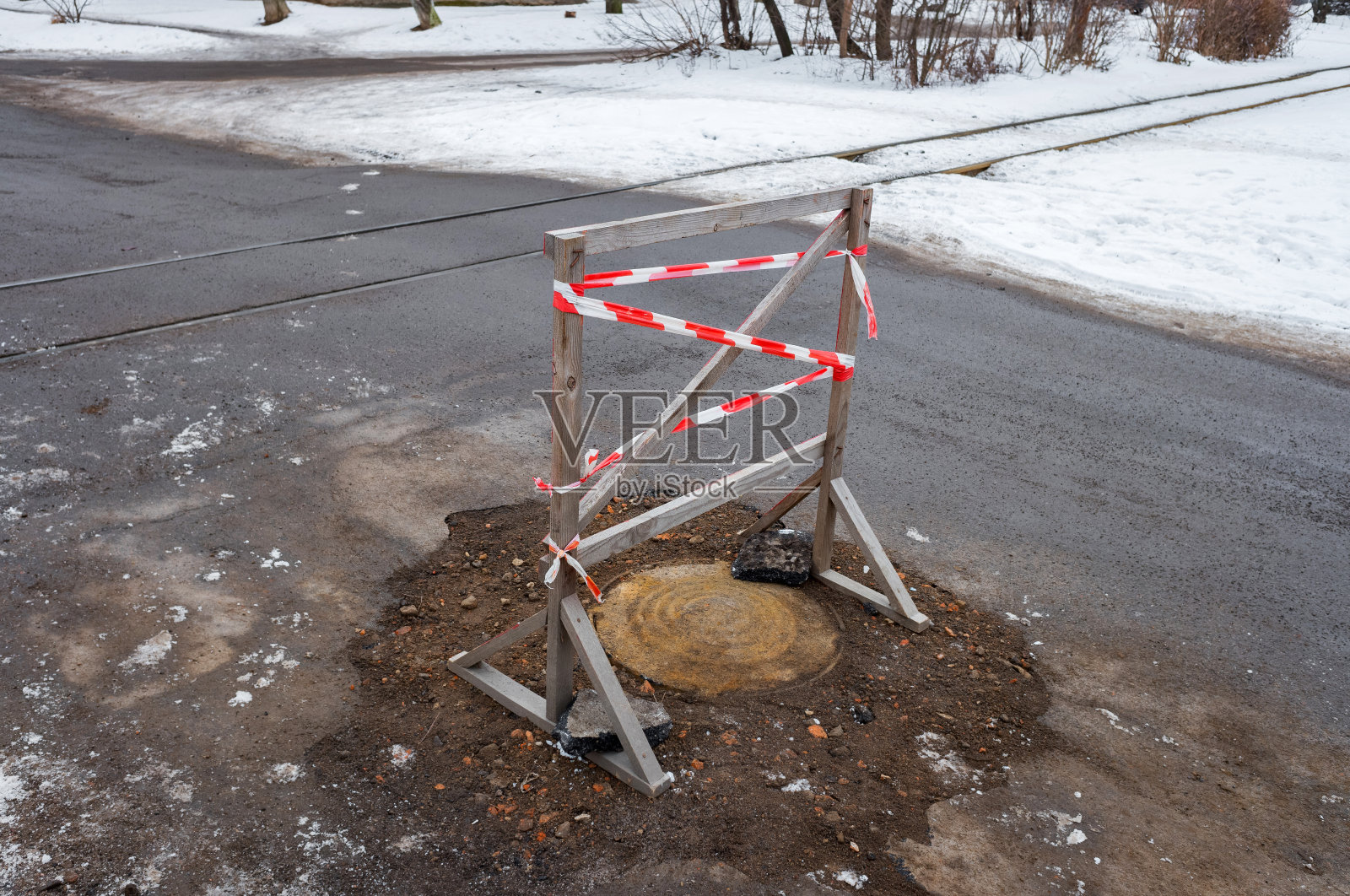 红色和白色的警告塑料胶带横跨在木制的屏障上。照片摄影图片
