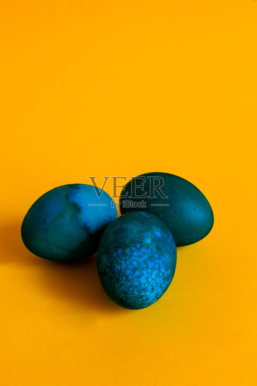 快乐的复活节假期。黄色背景上的三个蓝鸡蛋。照片摄影图片