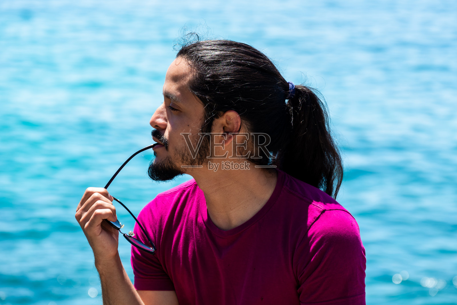 沙滩上一个留着黑色长发的拉丁青年照片摄影图片