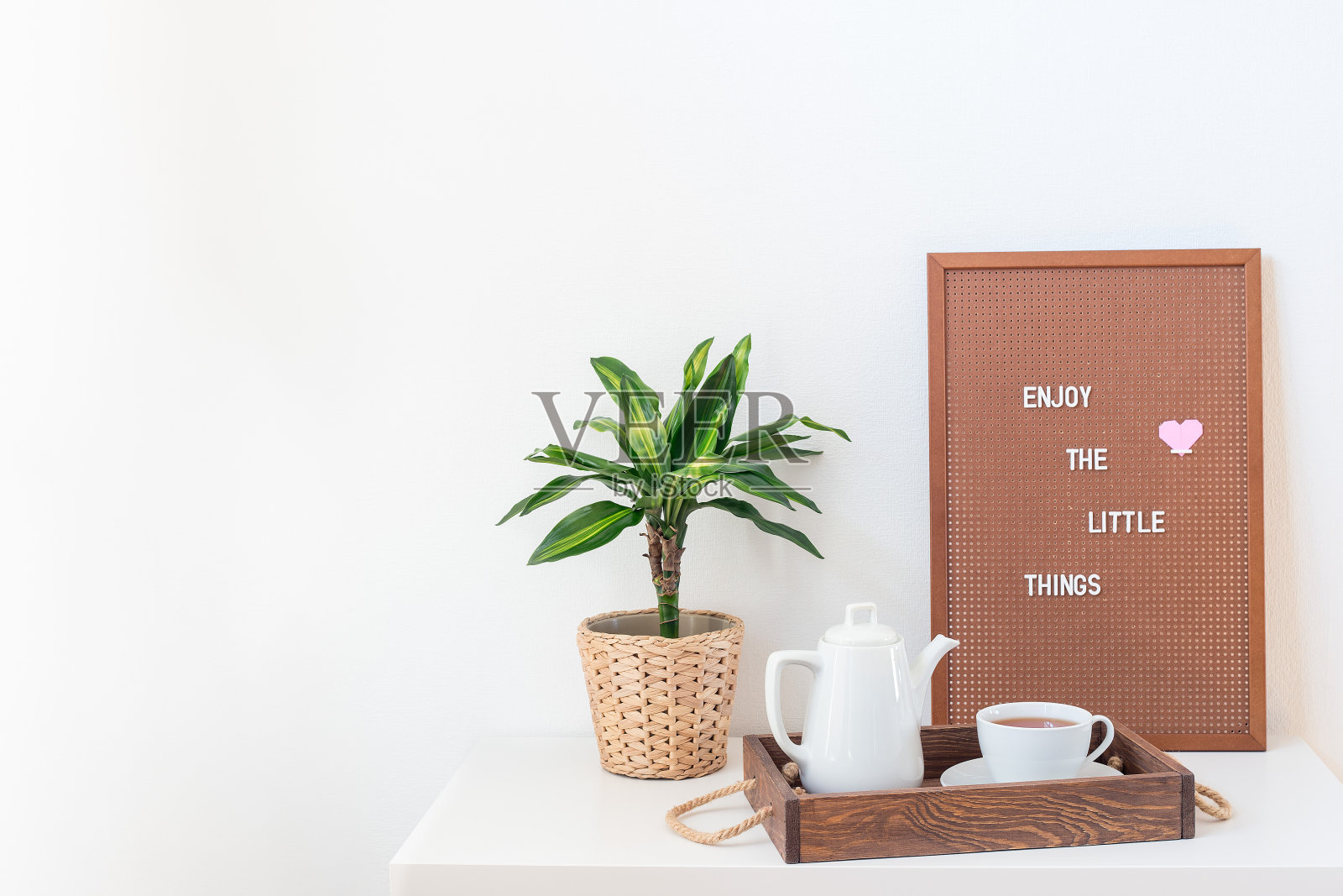 家庭内部与白色架子,绿色棕榈,钉板和托盘与茶壶和杯子,水平照片摄影图片