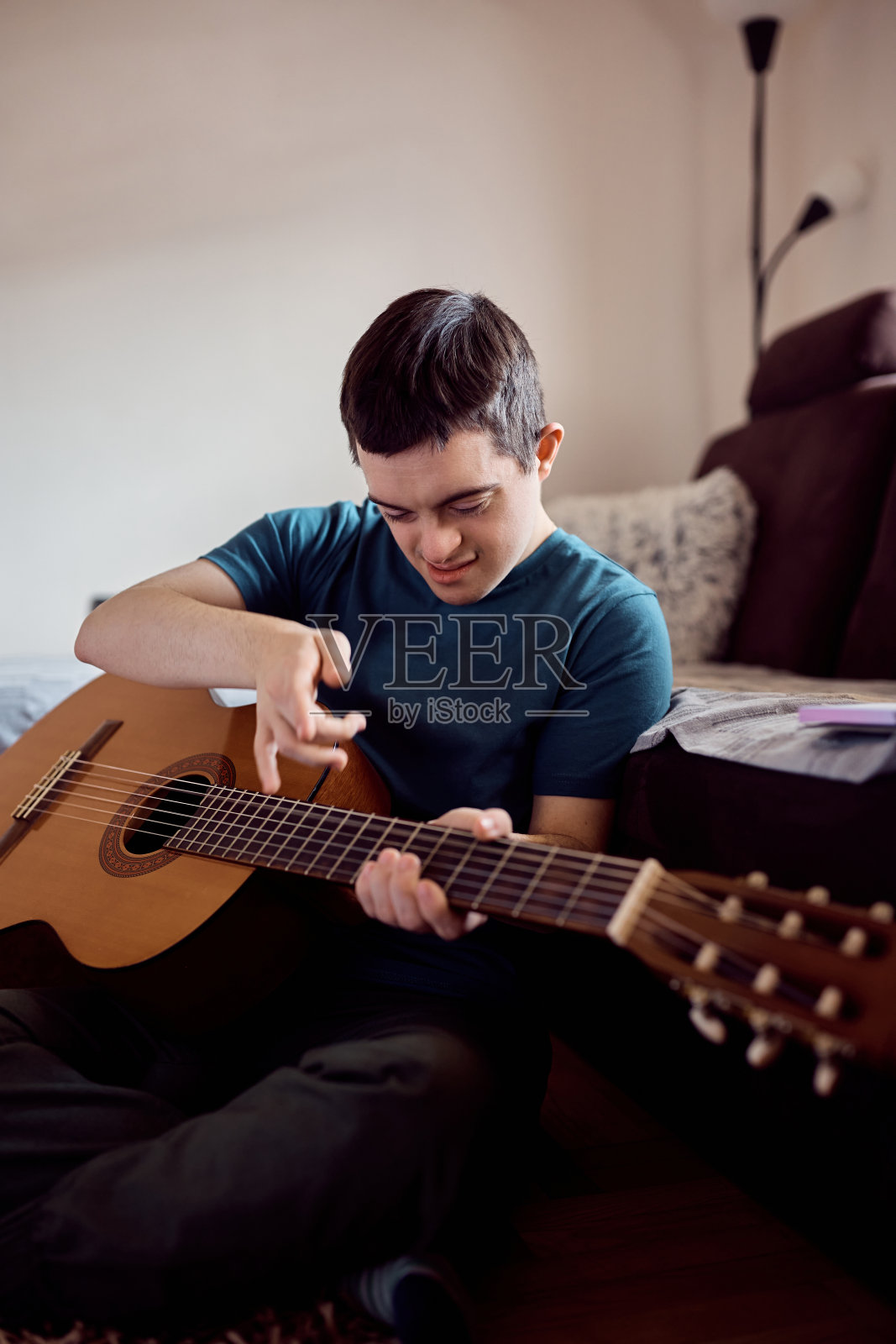 在家放松时弹奏原声吉他的唐氏综合征男子照片摄影图片