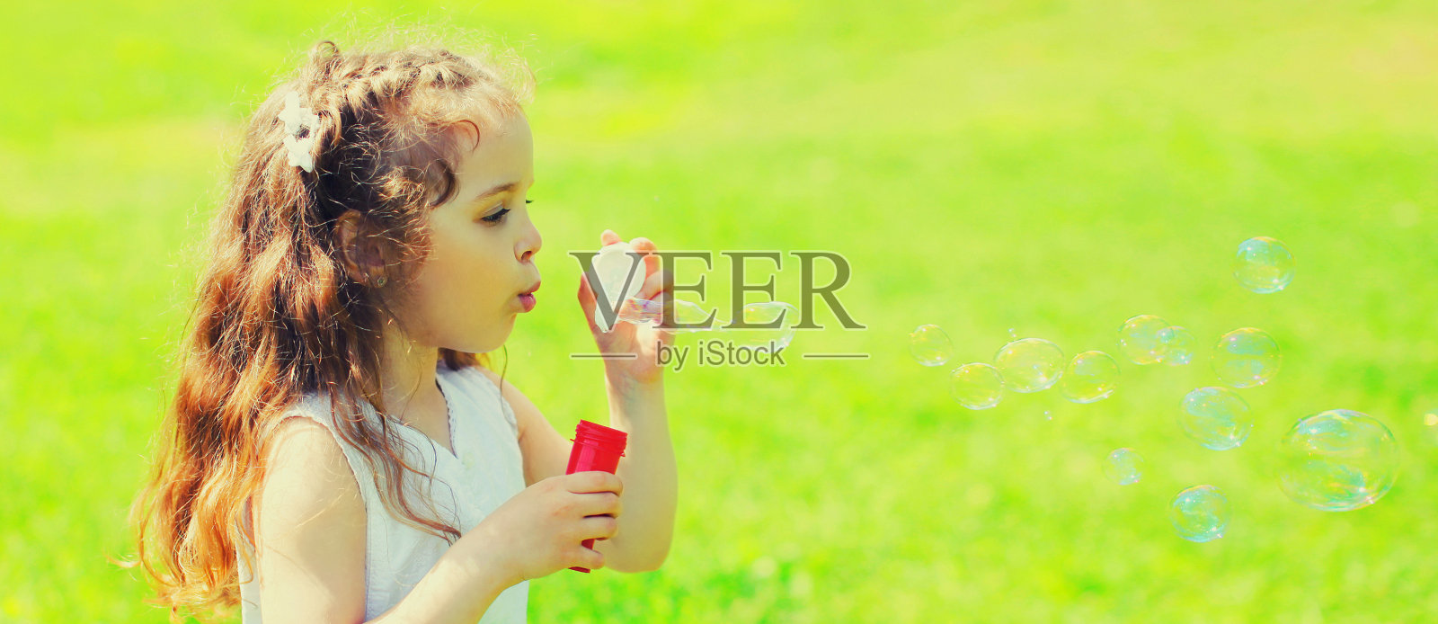 在夏天吹肥皂泡的小女孩的肖像照片摄影图片