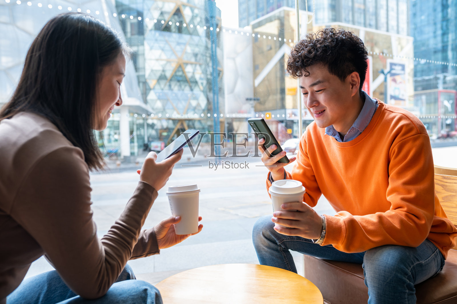 亚洲年轻异性恋夫妇在咖啡店使用智能手机照片摄影图片