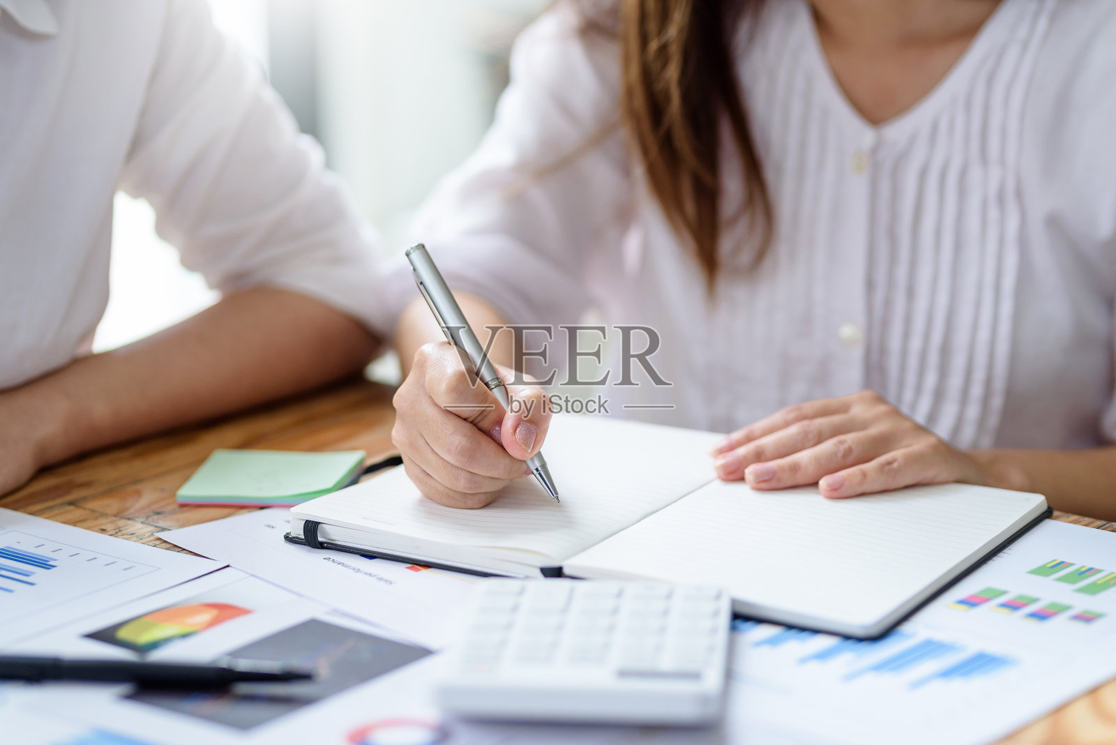 女人用笔在办公室做笔记的特写。照片摄影图片