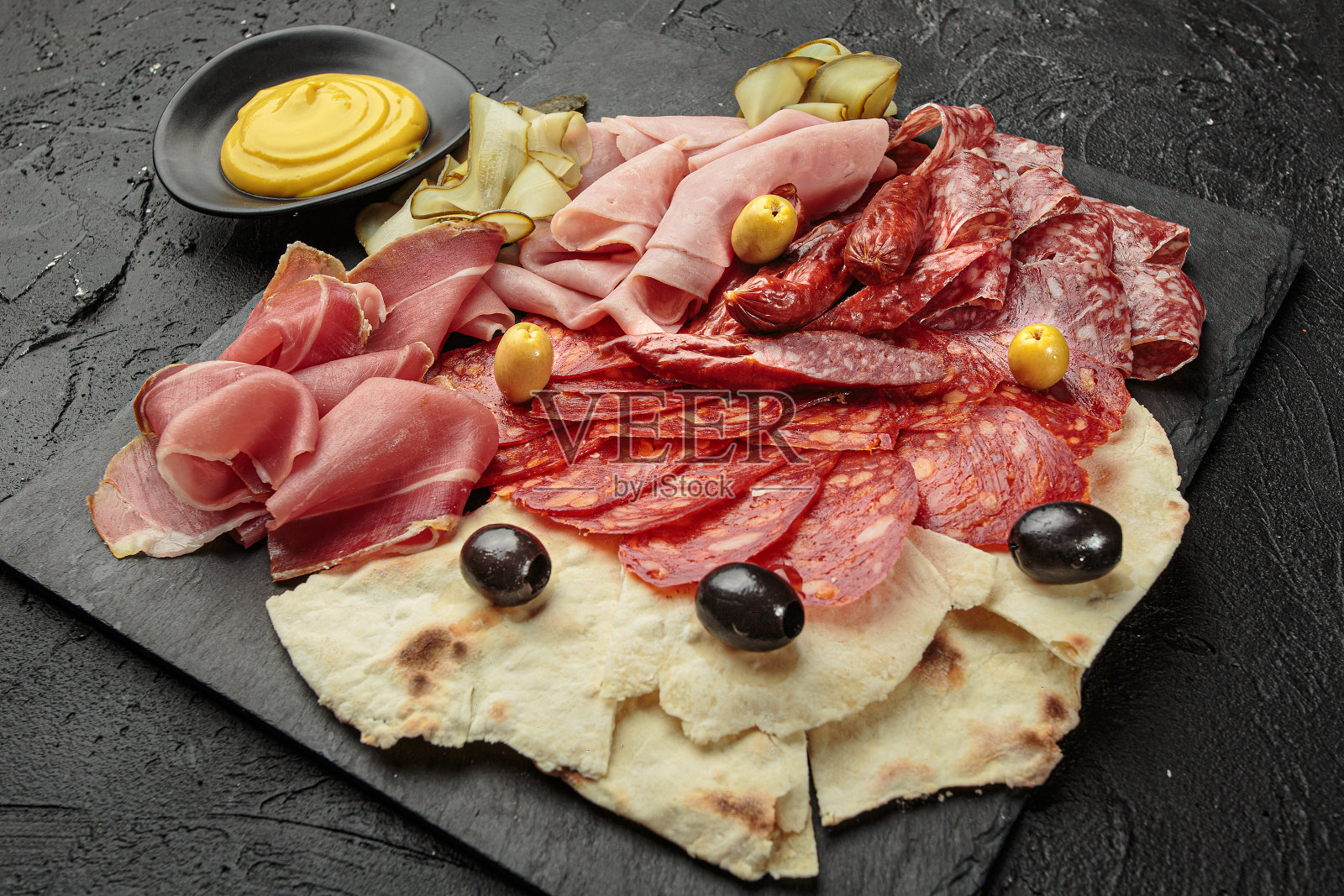 熟食板与各种泡菜和肉类-黄瓜,橄榄,意大利辣香肠,火腿和面饼照片摄影图片