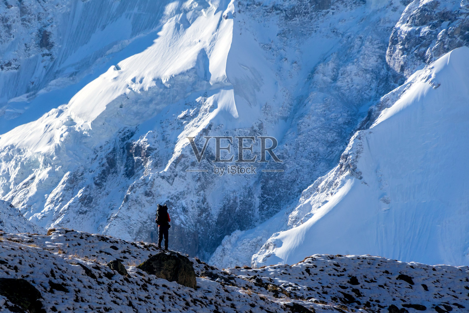 美丽的山景,巨大的蓝色冰川,一位中年登山者坐在那里,手里拿着对讲机呼叫等待救护车直升机的救援服务照片摄影图片