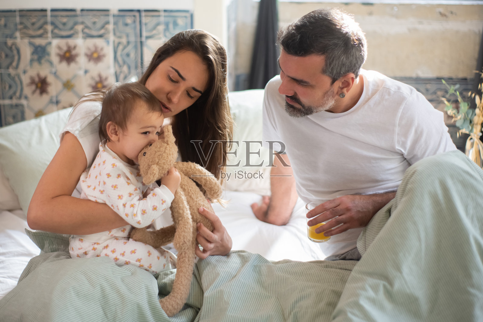 年轻的一家人醒来后坐在床上照片摄影图片