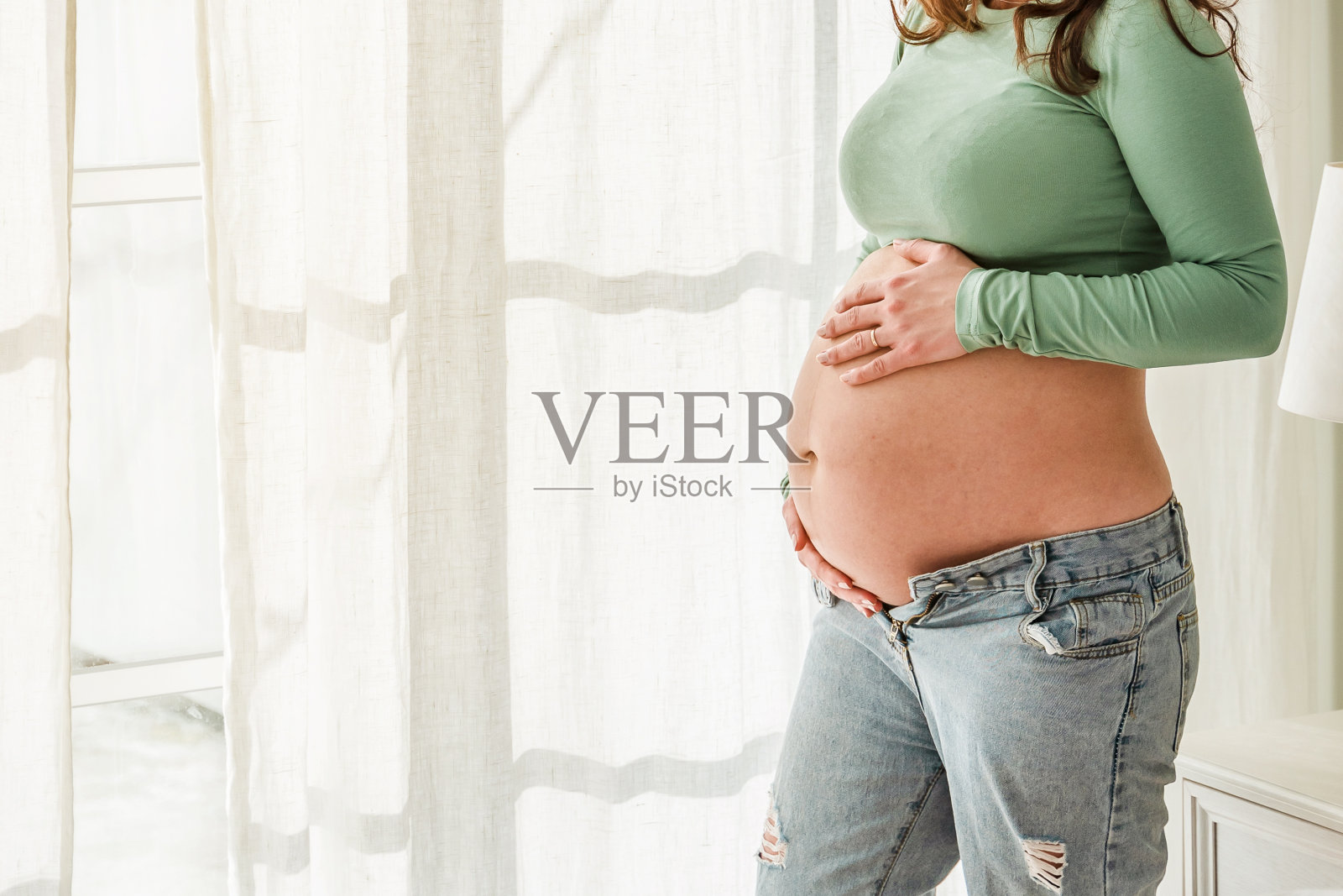 一个美丽的年轻孕妇在一个明亮的现代内饰。温柔的母亲概念,怀孕和婴儿等待照片摄影图片