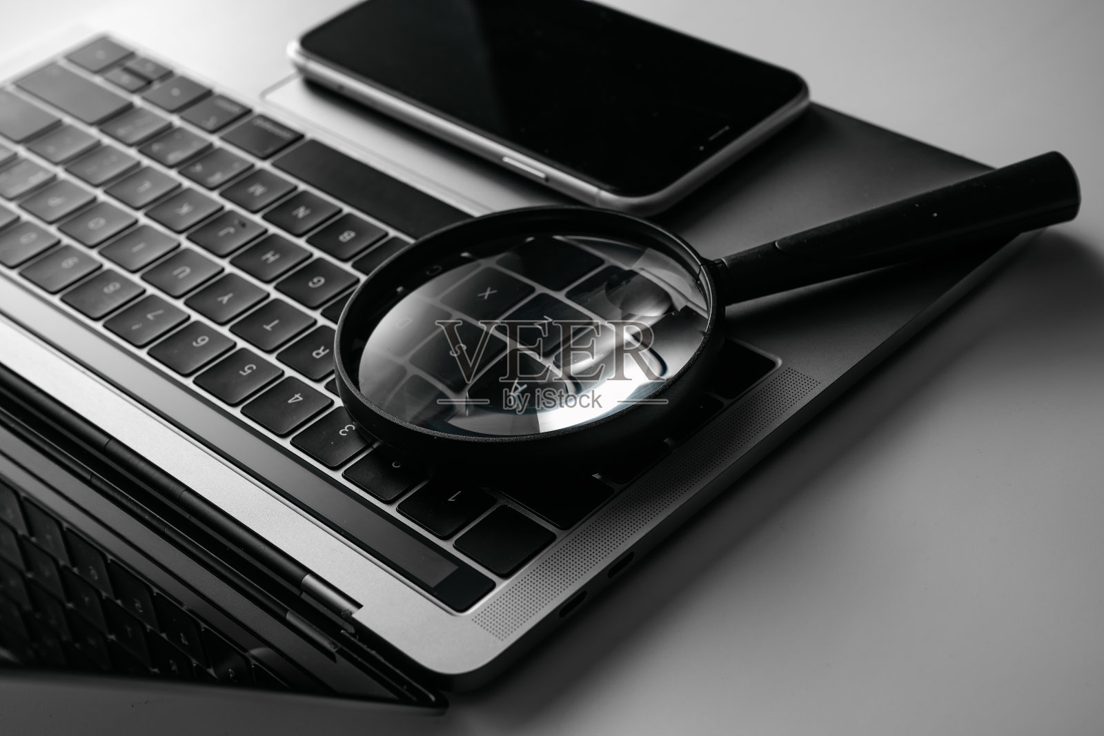 电脑,手机和放大镜在白色背景板上照片摄影图片