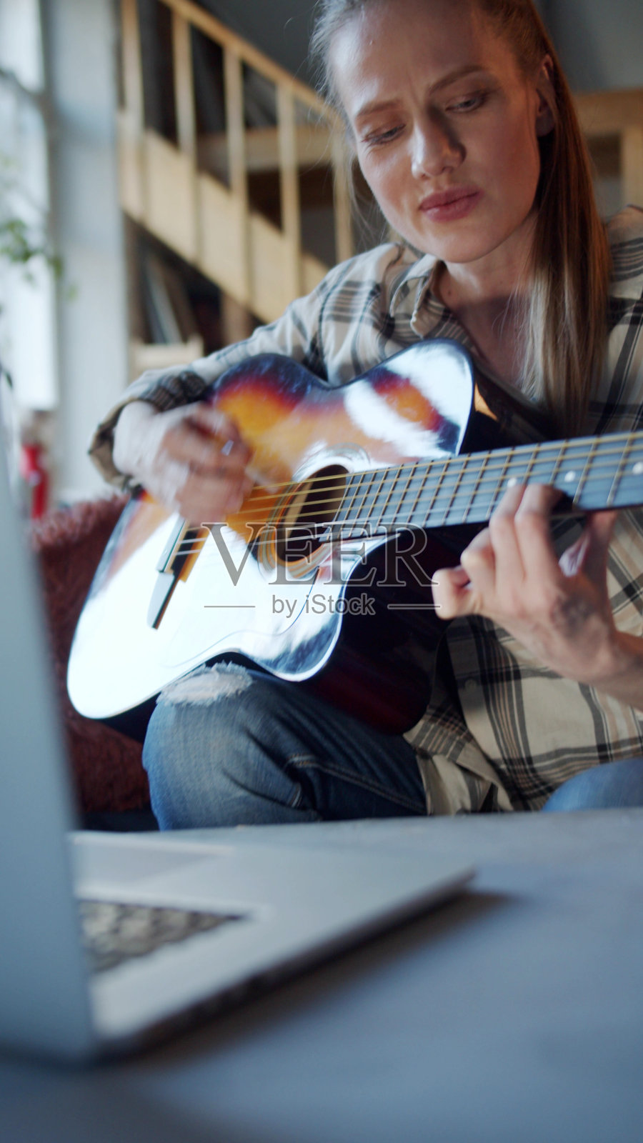一名女子通过网上的自学手册学习弹吉他照片摄影图片